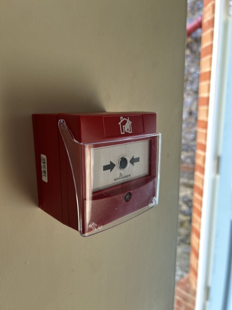 Red emergency call point on a wall.