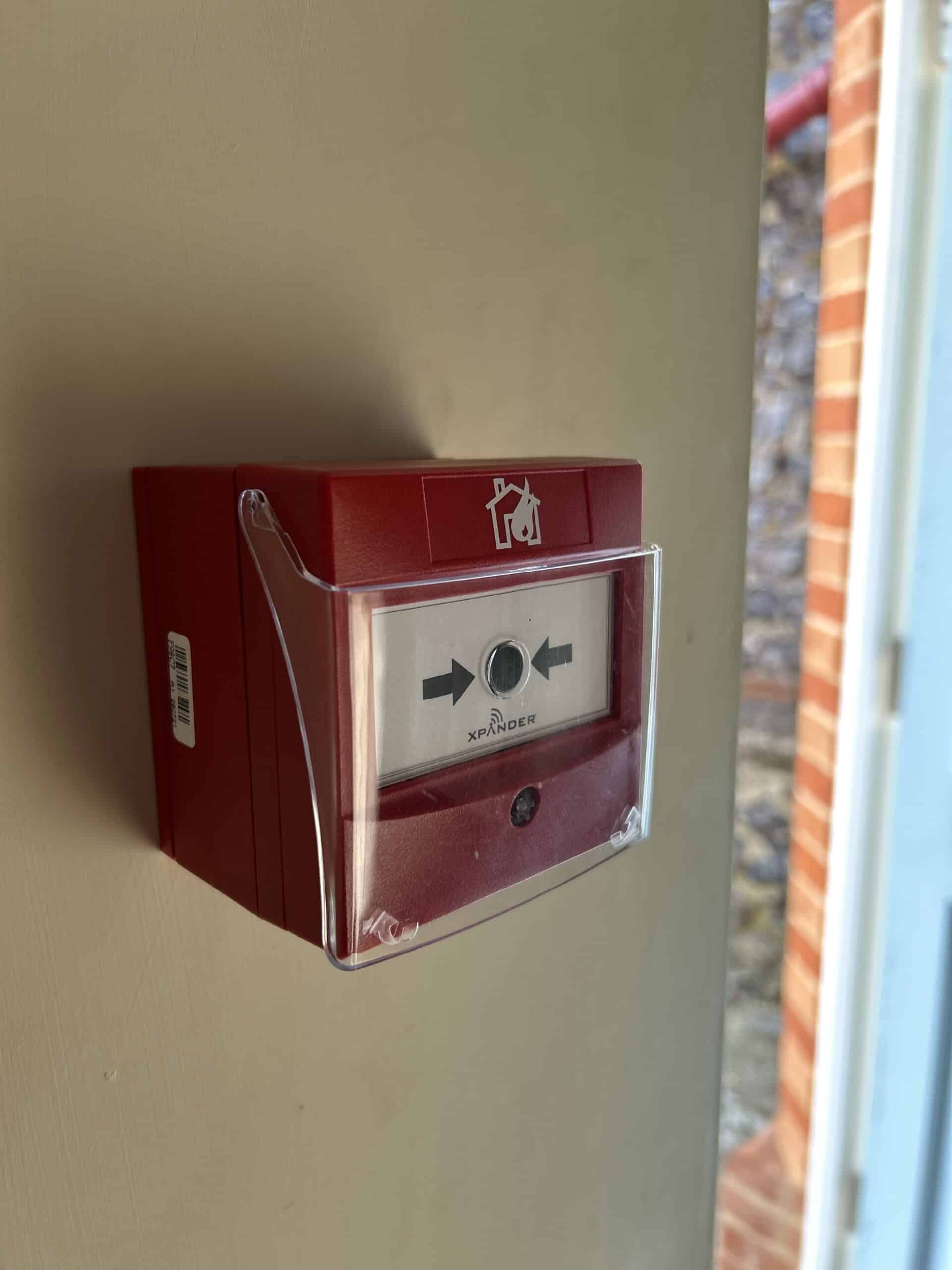 Red emergency call point on a wall.