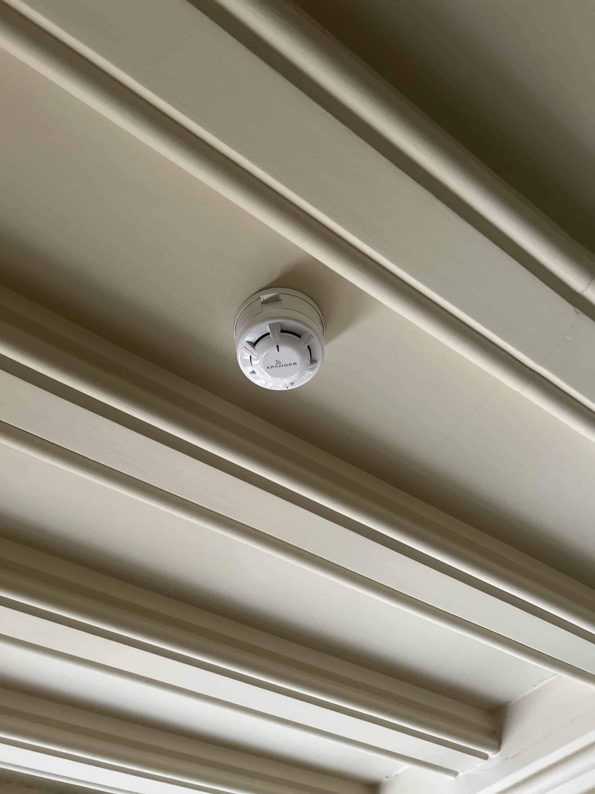 Ceiling-mounted smoke detector with decorative ceiling panels.