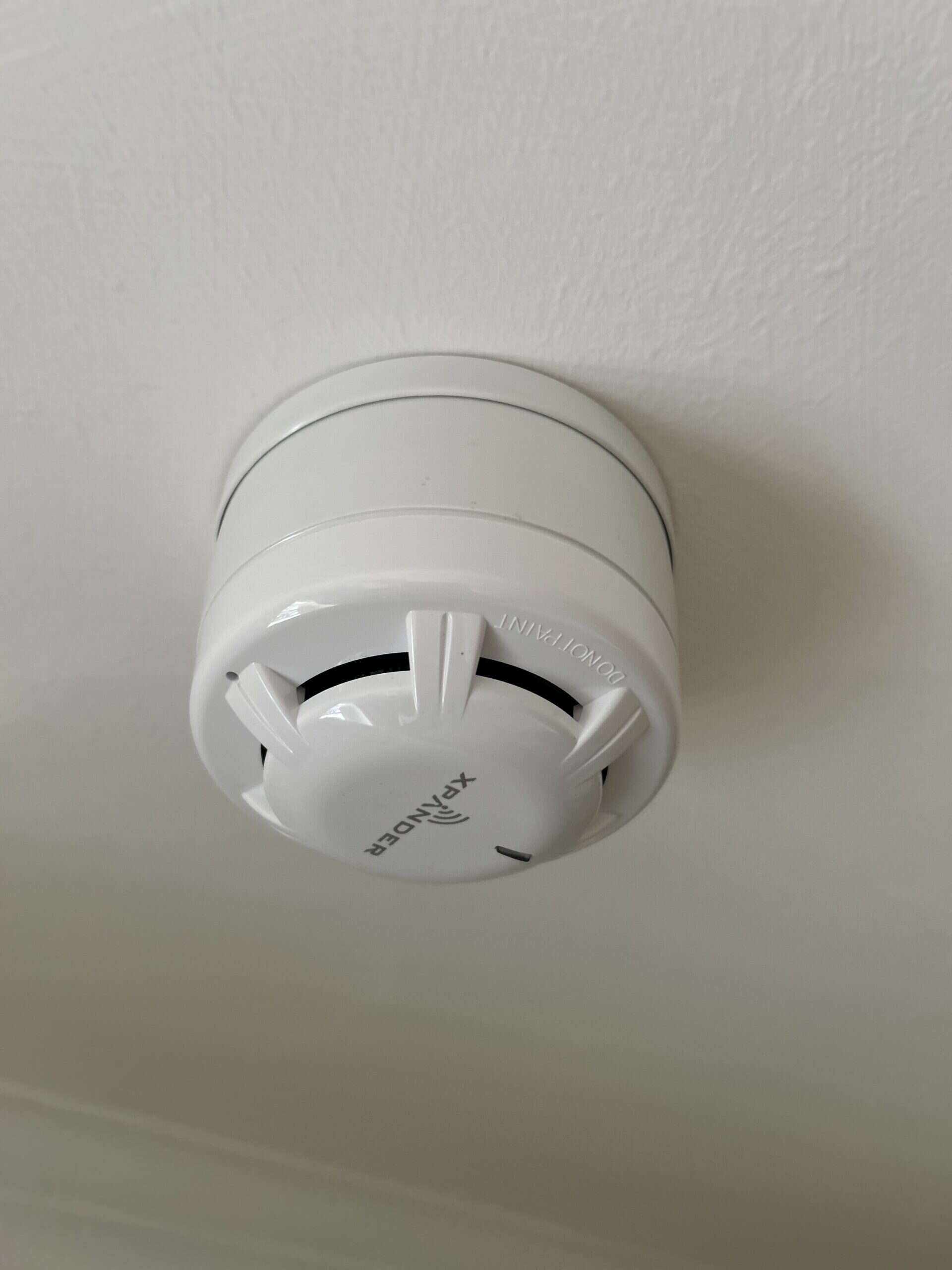 Ceiling-mounted smoke detector in white.