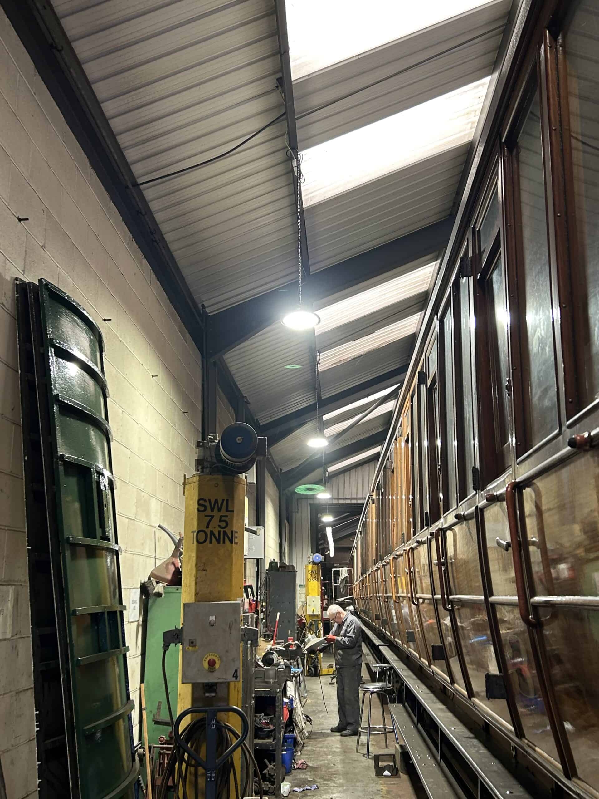 Man working on vintage train in workshop.