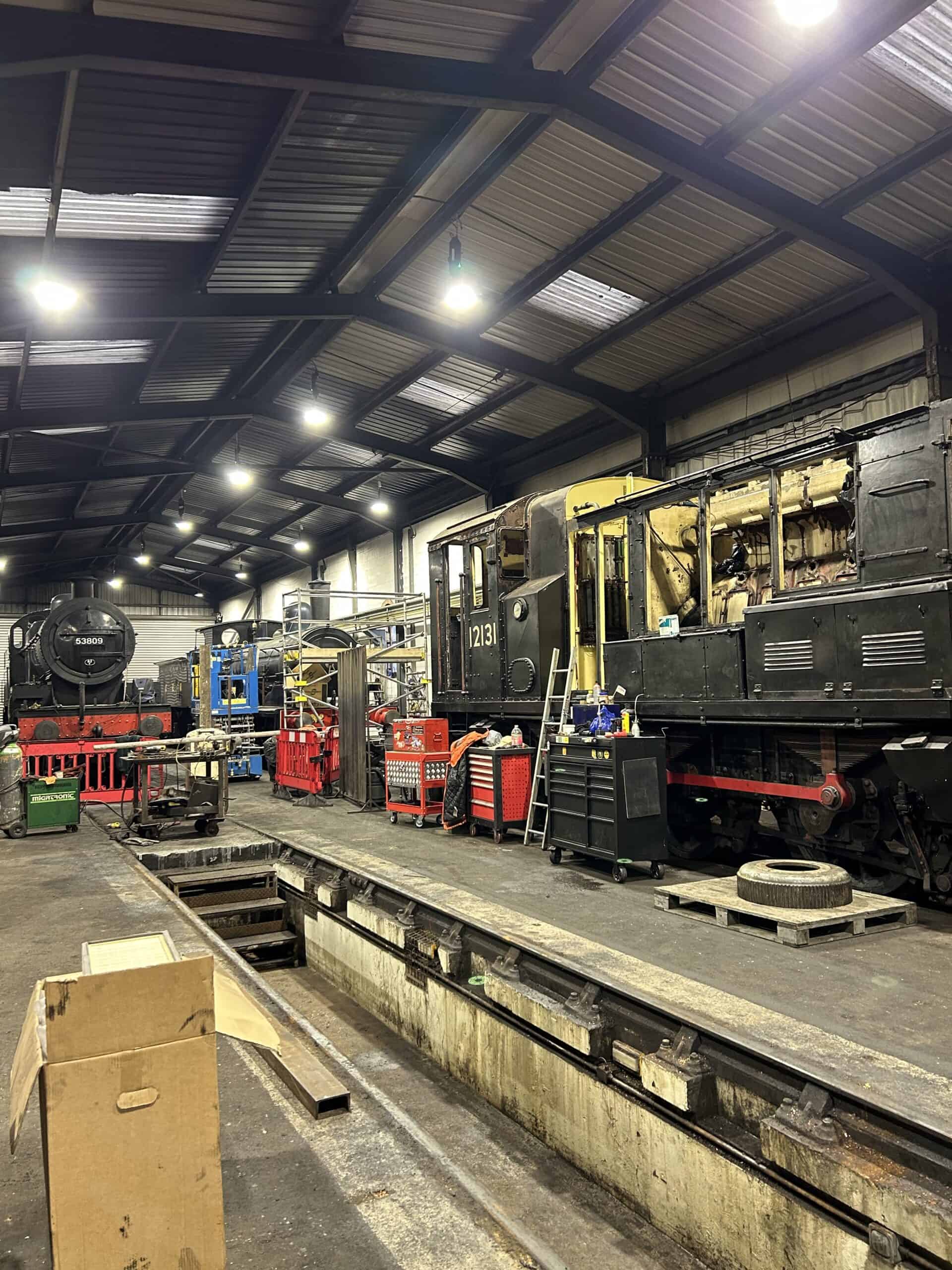 Inside a locomotive workshop with various engines.