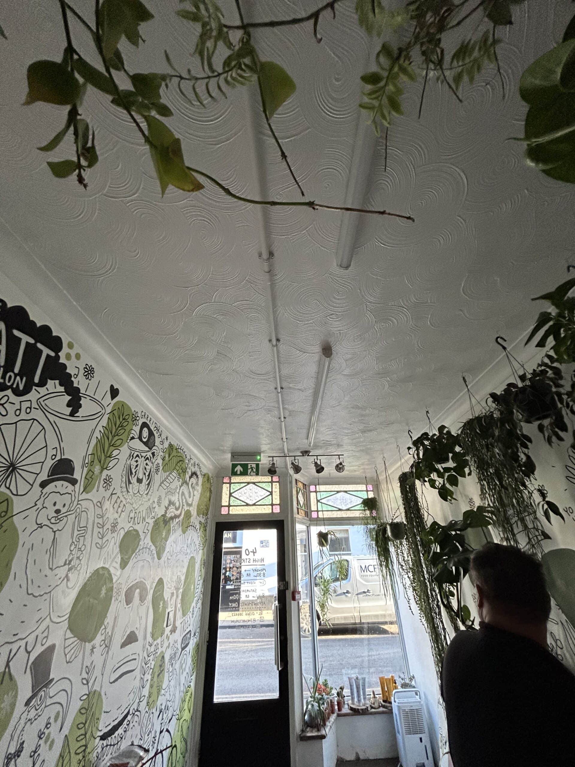 Interior with plants and mural in café hallway.