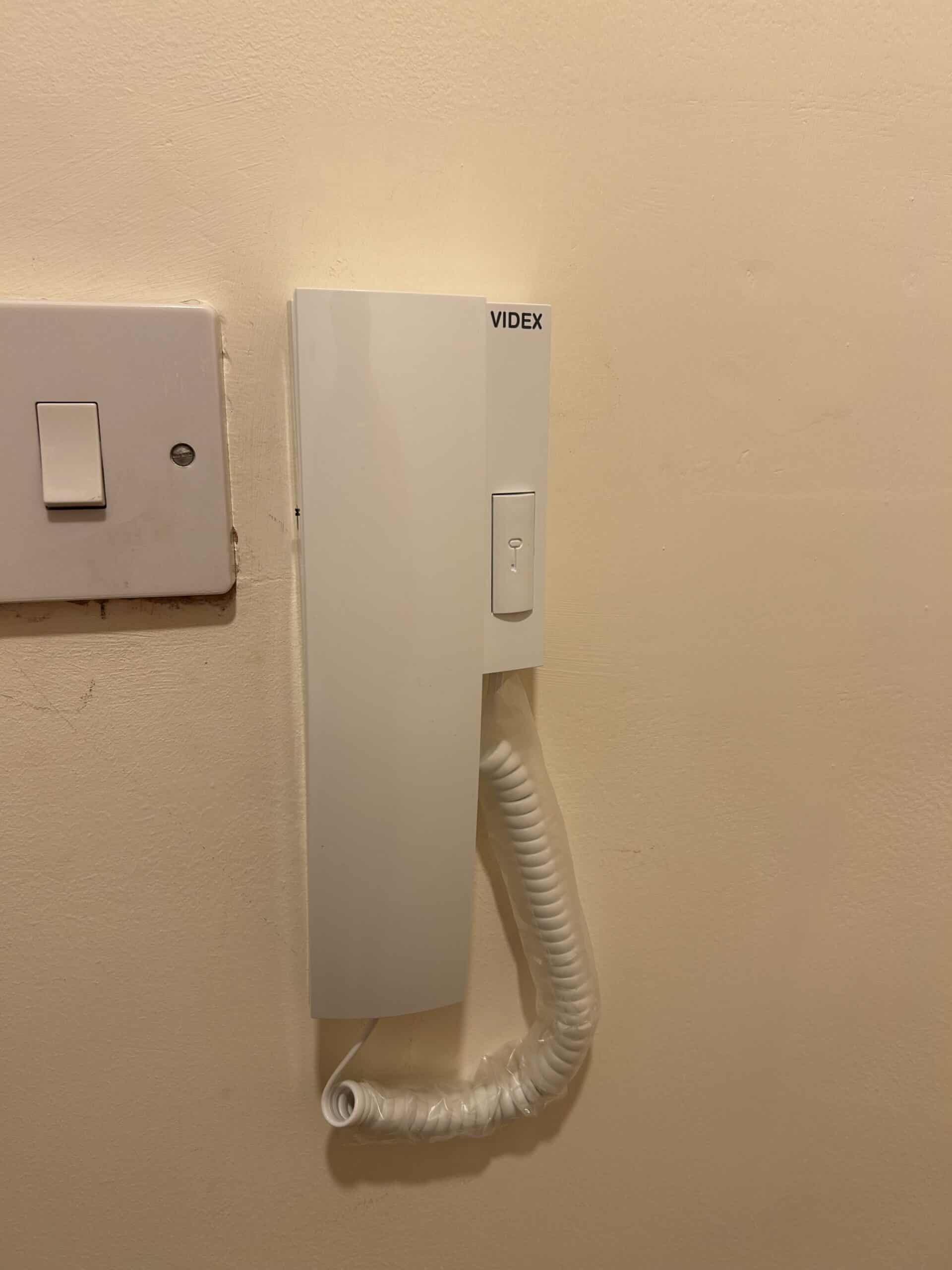 White intercom system mounted on beige wall.