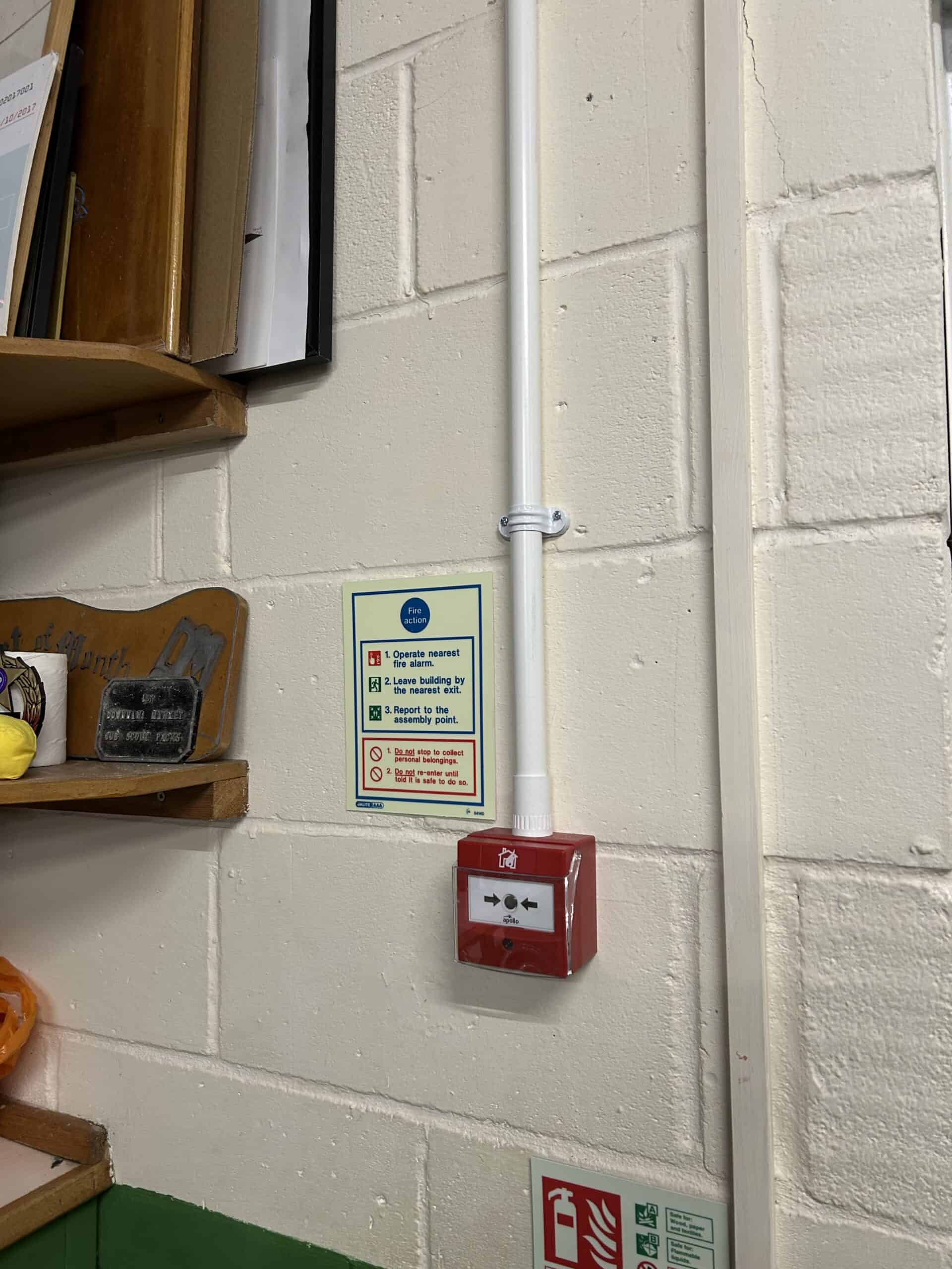 Fire alarm panel and emergency instructions on wall.
